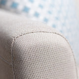 A close-up of a sofa's textured upholstery with the edge of a blue cushion in the blurry background.