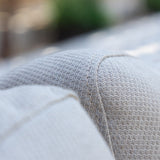 A close-up view of a pillow with a textured fabric and visible stitching against a blurred background.