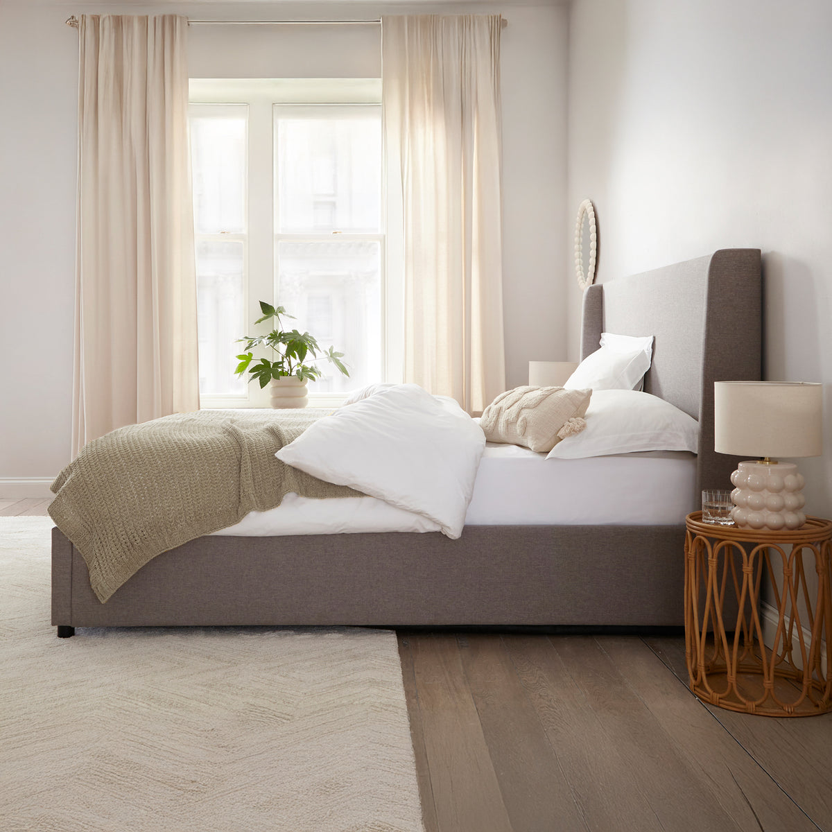 Brent Ottoman Storage Bed Frame from Roseland Furniture- Modern bedroom with a bed, side table, and lamp.