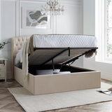 A natural upholstered ottoman bed with a lifted mattress reveals storage underneath, positioned against a paneled wall on a herringbone wood floor.