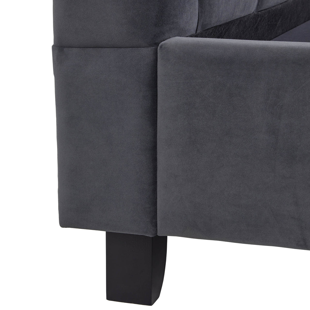A close-up of a dark grey sofa corner with a visible black leg against a white background.