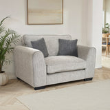 Thornby Snuggle Chair Light Grey Charcoal from Roseland Furniture positioned in a living room or lounge with white walls and light oak flooring, on the left is a plant on the right in the background is a dining room, above is a piece of abstract artwork and covering the floor is a light cream colour rug.