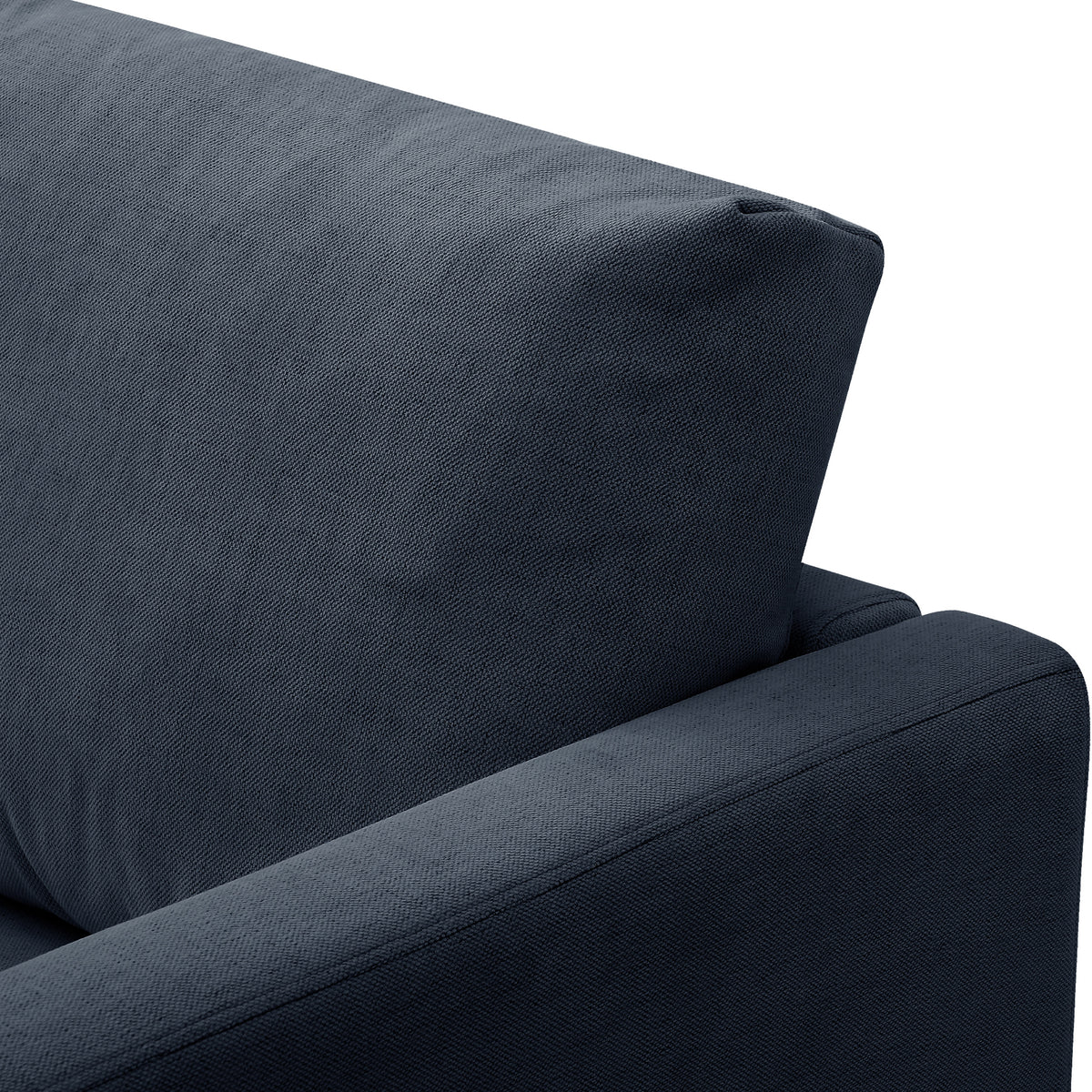 A navy blue fabric sofa against a stark white background, focusing on the armrest and backrest.