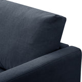 A navy blue fabric sofa against a stark white background, focusing on the armrest and backrest.
