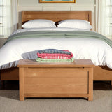 Surrey Oak Blanket Box at the end of a wooden bed from Roseland Furniture