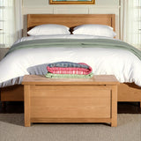 Surrey Oak Blanket Box at the end of a wooden bed from Roseland Furniture