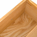 A wooden corner showing the joint of two planks, with visible wood grain against a white background.