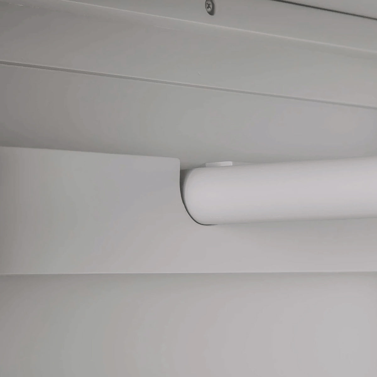 A cylindrical object, possibly a blind or a shade, is rolled up near the ceiling; it suggests an interior setting. No actions or text are present.