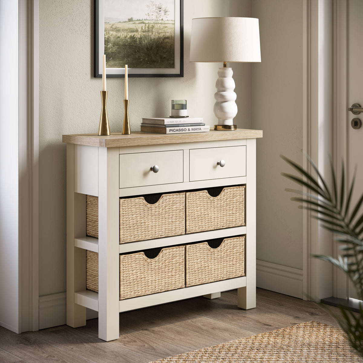 Farrow Basket Console Table from Roseland Furniture decorated with books, candles, and a lamp in a room
