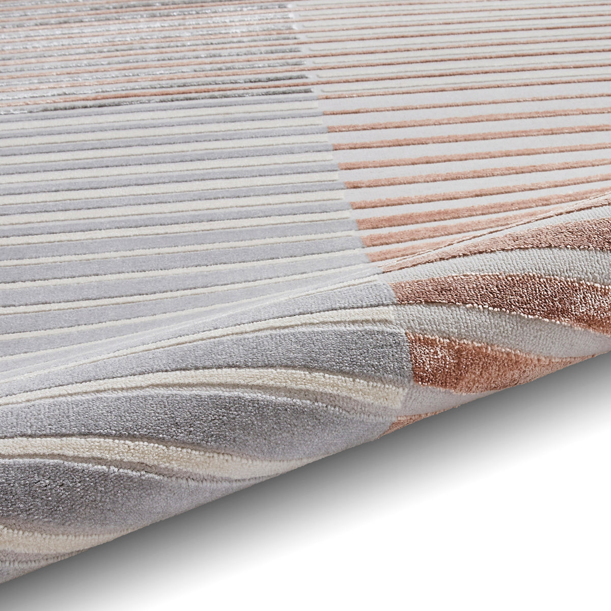 A striped rug with varying shades of gray, white, and rose lies flat, showcasing its texture and color gradient.