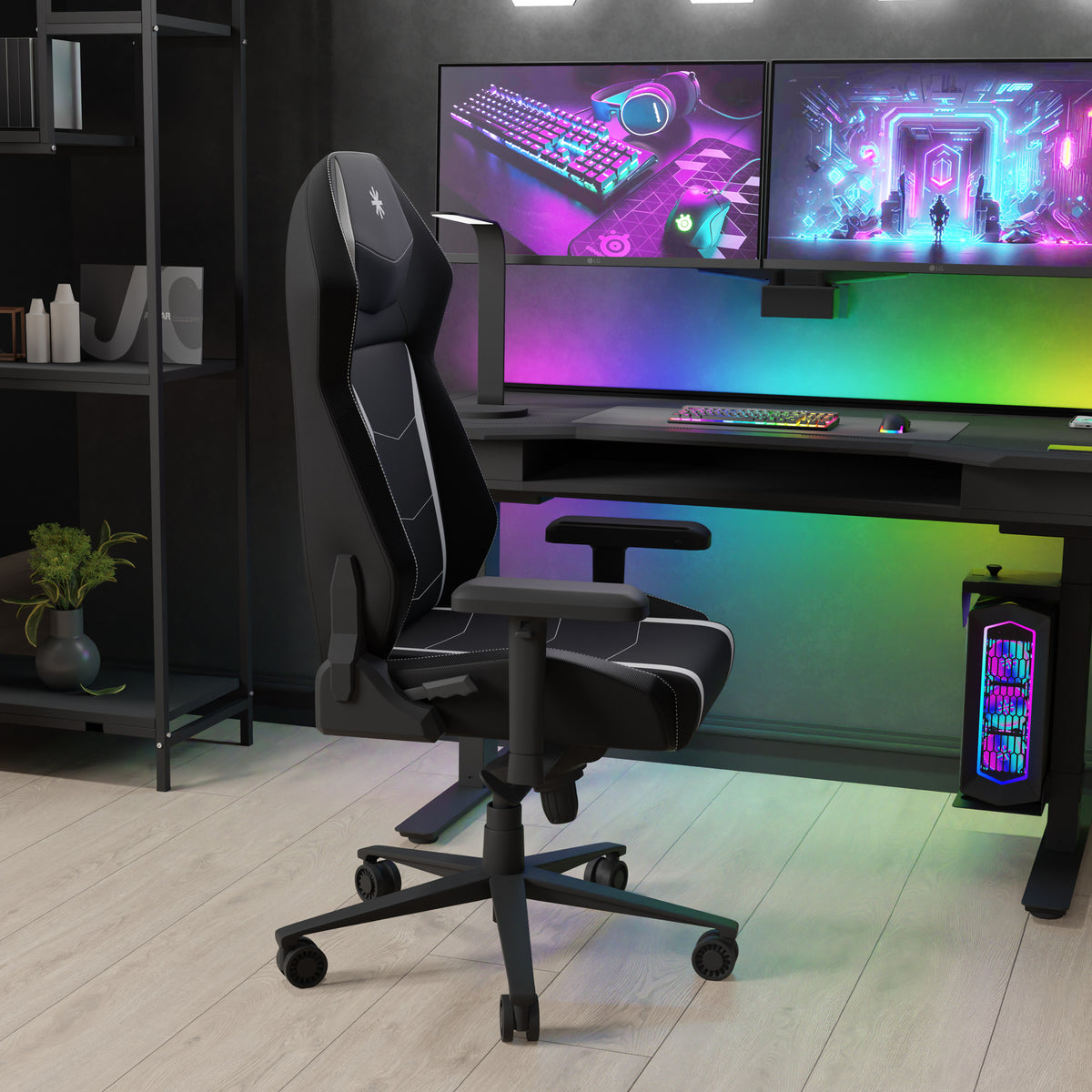 Ergonomic gaming chair positioned in front of a desk with multiple monitor setup, colorful backlighting, and a modern gaming PC tower, in a dark room with shelving.