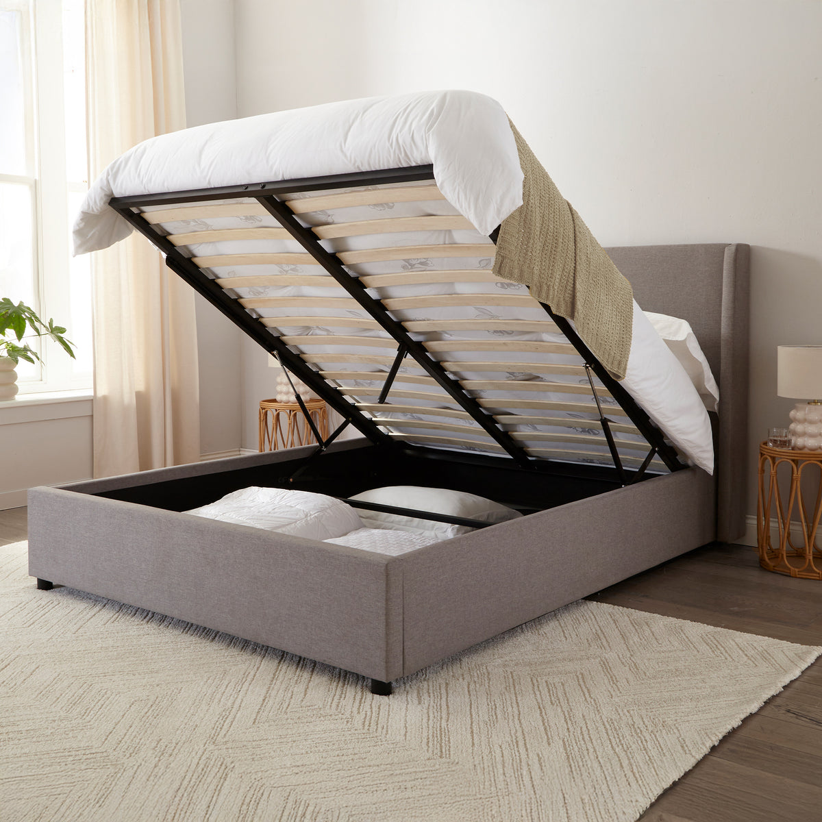 Brent Ottoman Storage Bed Frame from Roseland Furniture- Gray upholstered bed with raised headboard in a bedroom setting