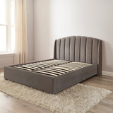 Gray upholstered bed in a room with a window and beige curtains.