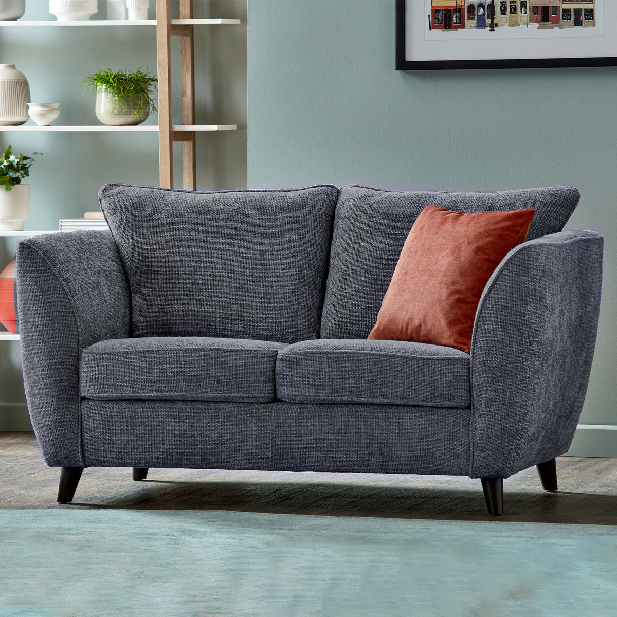 A grey fabric loveseat with plush cushions and rounded armrests, in a living room.