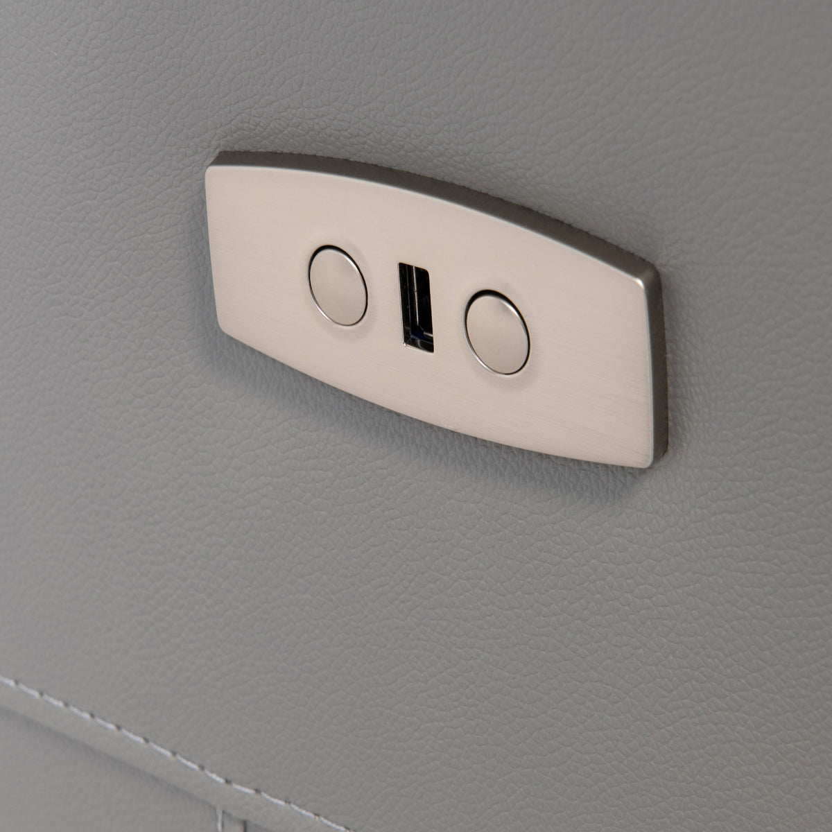 A metallic coat hook with two circular indents is mounted on a textured gray surface, providing a place to hang items.