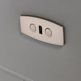 A metallic coat hook with two circular indents is mounted on a textured gray surface, providing a place to hang items.