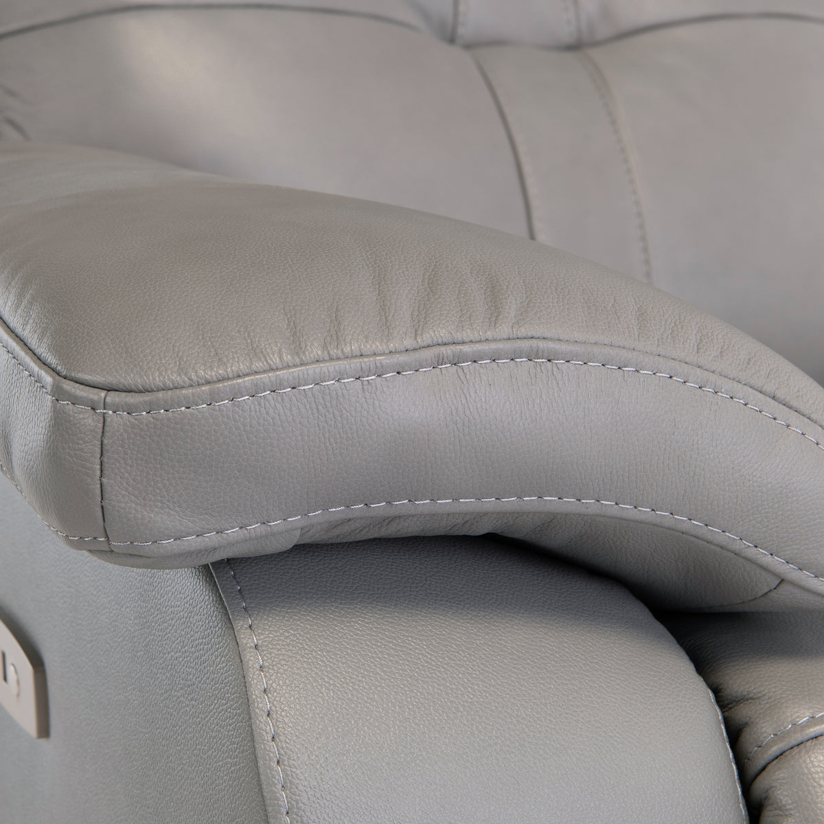 A close-up of a gray leather armchair with prominent stitching, highlighting texture and comfort.