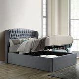 An open gray storage bed with a lifted mattress reveals a spacious compartment underneath, situated against a paneled wall on a herringbone-patterned wooden floor.