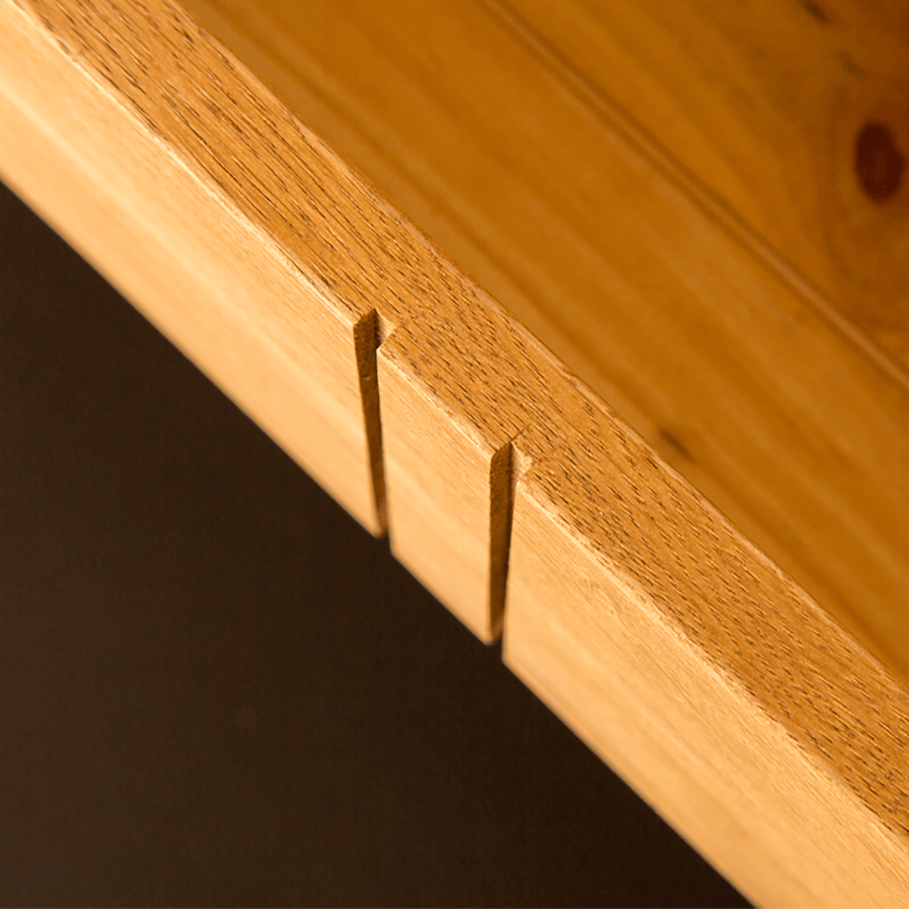 Wooden dovetail joints protrude from a panel, demonstrating craftsmanship against a dark background.