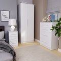White furniture including a wardrobe, chest of drawers, and bedside table, arranged in a bedroom with a framed picture reading "our happy place."