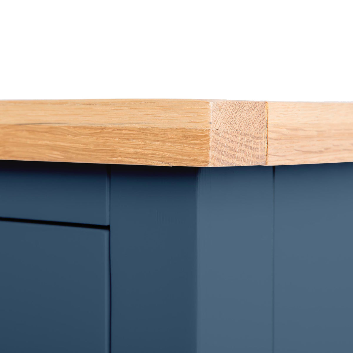 A wooden table edge with a visible grain, attached to a blue surface, possibly a drawer. The setting seems to be indoors with studio lighting.