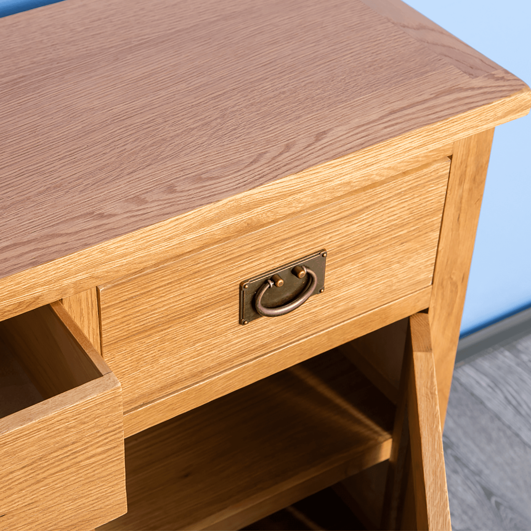 A wooden desk with an open drawer, revealing storage space, set against a blue and grey backdrop.