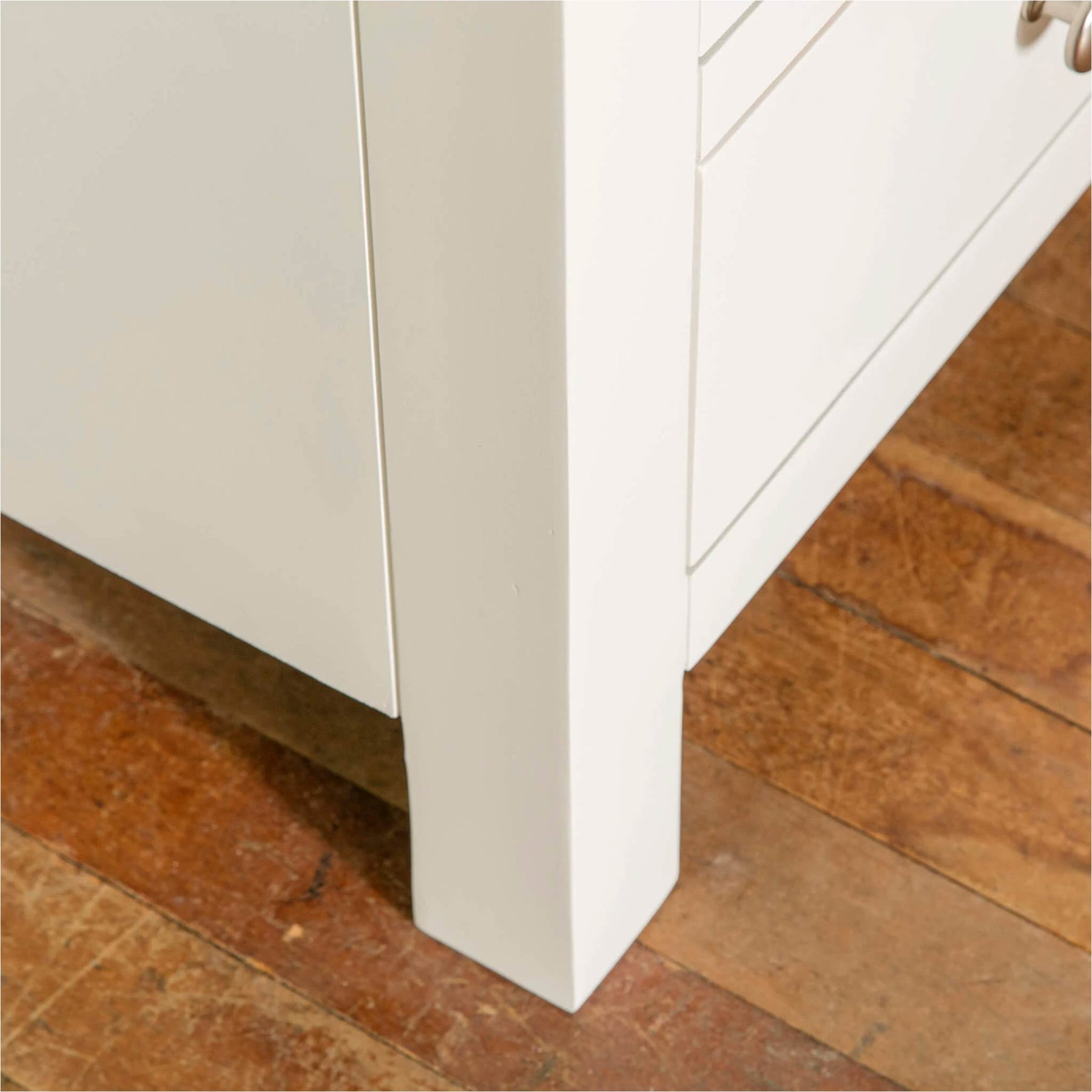Farrow White 2 Over 3 Chest Of Drawers from Roseland Furniture - close up of front leg