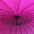 A vibrant pink umbrella is open, revealing its black structural framework against a bright fabric background.