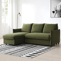 A green sectional sofa with chaise lounge sits on a patterned rug, under a floor lamp, beside a large window, with an art frame on the wall.