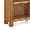 Zelah Oak Narrow Bookcase - Close up of lower shelf and feet