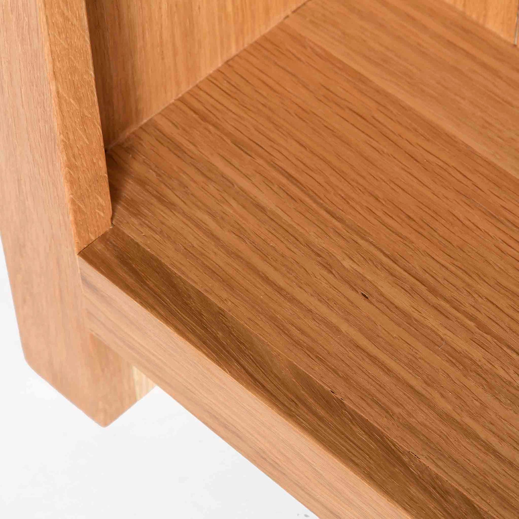 A close-up of a wooden structure showcasing the detail of the wood grain; appears to be a part of furniture, possibly a chair or table, against a white background.
