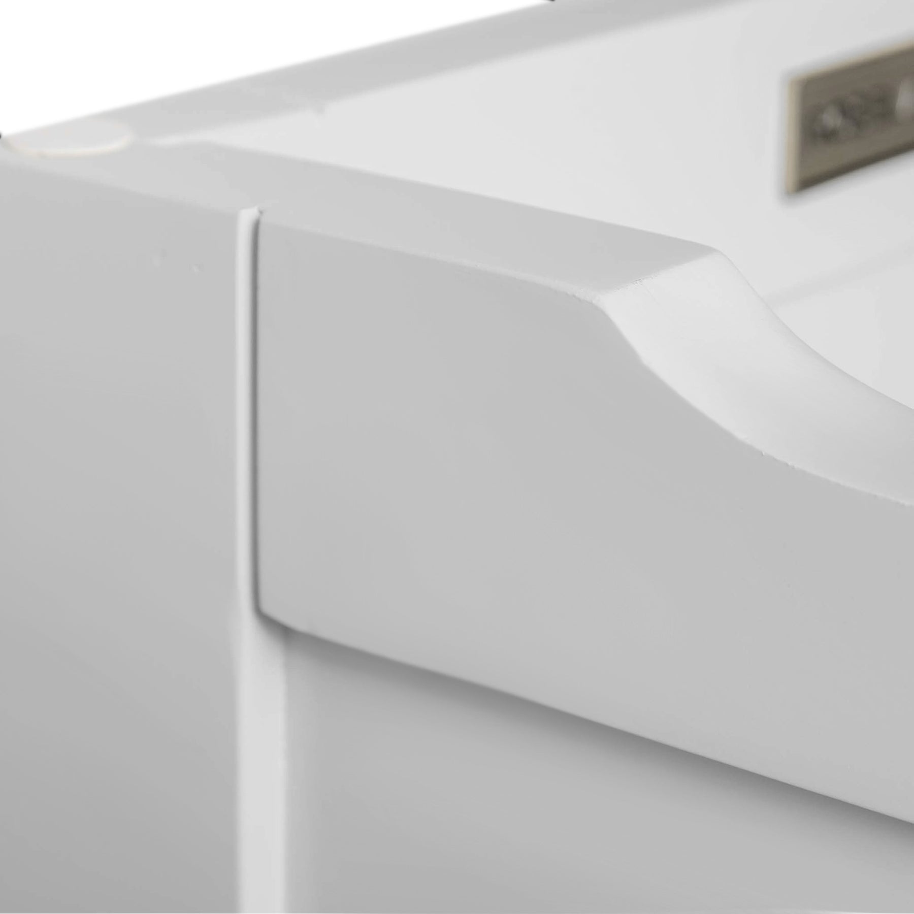 A close-up of a white, textured object with a curved edge, against a blurred background, possibly part of furniture or appliance.