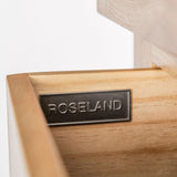 A metal plaque with the word "ROSELAND" is mounted on a wooden surface, against a white background.