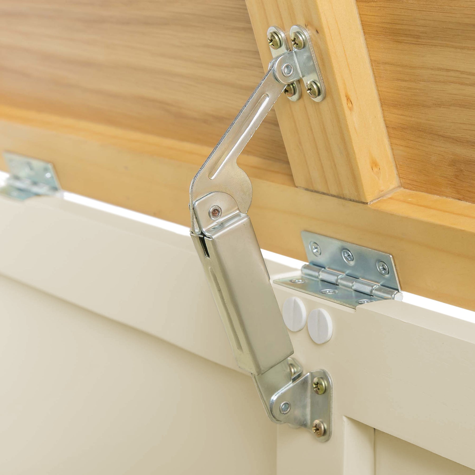 A metal hinge mechanism connects a wooden cabinet door to its frame, stabilizing the door in an open position.