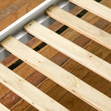 Three wooden slats are placed parallel on a brick surface, with visible black straps underneath them, indicating they're part of a pallet or crate.