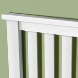 A white radiator against a green wall, with angular shadows casting on the wall, illustrating light, warmth, and domesticity.