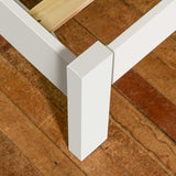 A white, rectangular table leg supports a table top against a terracotta-tiled floor.