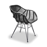 A black, modern style chair with slender metal legs and an intricately woven seat, is standing idle against a white background.