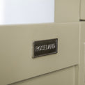 Close up of the metal Roseland door label on the Chichester Ledum Green Corner Cupboard
