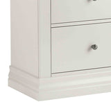 A white, two-drawer nightstand with round metal knobs, partially cropped on a plain background.