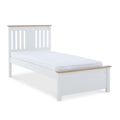 A single white bed with a mattress, featuring a simple headboard and footboard, isolated against a white background.