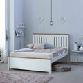 A white, wooden bed with neutral bedding is staged in a clean, gray-walled room adorned with heart ornaments, displaying a serene and tidy bedroom setting.