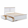 A white wooden double bed frame stands stationary, featuring a slatted headboard and two under-bed storage drawers, set against a pure white background.