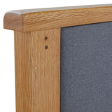 A wooden frame with visible grain details borders a textured grey fabric, suggesting a piece of furniture or a pinboard.
