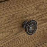 A vintage-style metal drawer knob projects from a wooden surface, illustrating a detail of furniture design.