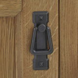 A dark metal door knocker is mounted on a light wooden door, featuring a simple, traditional design.