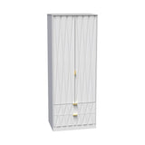A tall white wardrobe with a textured design stands closed against a plain backdrop. The wardrobe features two doors and two lower drawers with golden handles.