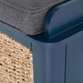 A grey cushion rests atop a navy plastic chair, with a woven mat partially visible in the background.