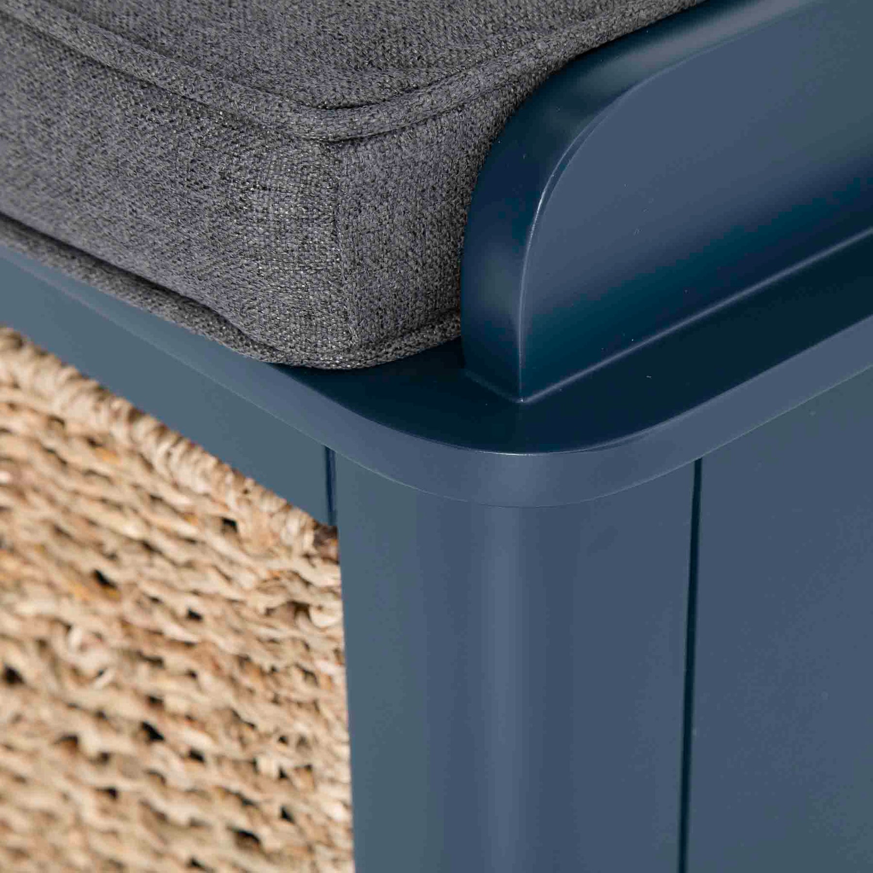 A grey cushion rests atop a navy plastic chair, with a woven mat partially visible in the background.