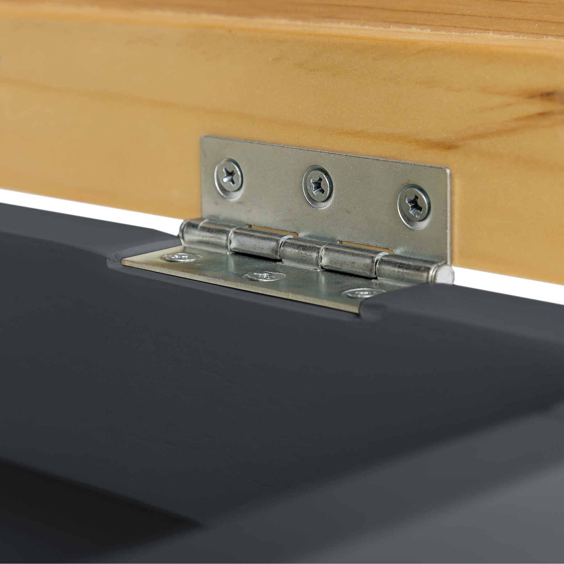 A metal hinge connects a light wooden panel to a black surface, illustrating a junction of materials possibly within a piece of furniture.